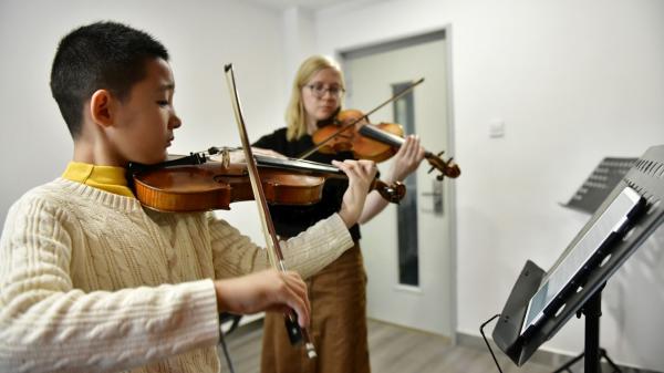 a student and a teacher playing the violin together